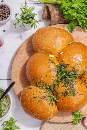 Aromatic garlic buns. Fresh baked goods, a traditional gluten-free soup snack. Parsley, spices, olive oil. Hard light, dark shadow, white wooden background, top viewの写真素材