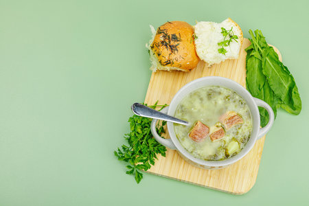 Traditional Portuguese soup Caldo Verde with fresh bakery. Aromatic greens, served dish, ready to eat healthy food. Modern wooden stand, green background, top viewの写真素材