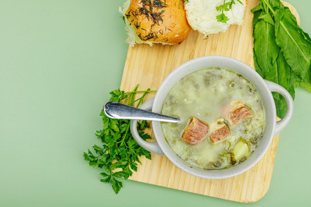 Traditional Portuguese soup Caldo Verde with fresh bakery. Aromatic greens, served dish, ready to eat healthy food. Modern wooden stand, green background, top viewの写真素材