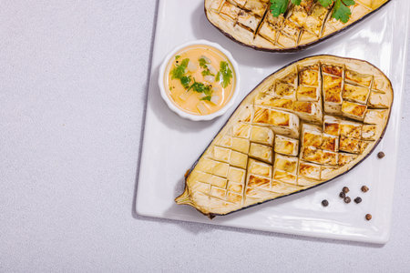 Grilled eggplants with olive oil, garlic and greens. Traditional food for picnic or barbecue, vegan healthy eating. Modern hard light, dark shadow, stone concrete background, top viewの写真素材