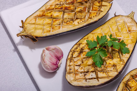 Grilled eggplants with olive oil, garlic and greens. Traditional food for picnic or barbecue, vegan healthy eating. Modern hard light, dark shadow, stone concrete background, close upの写真素材