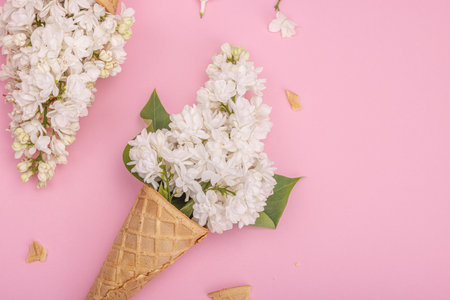 White lilac flowers in waffle ice cream cones on pink background. Flat lay, traditional spring concept, top viewの写真素材