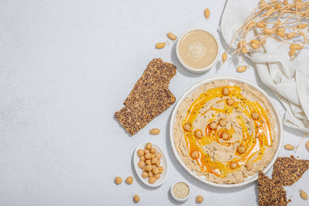 Hummus with olive oil and crispy bread. Indispensable ingredient for a healthy lifestyle. Comfort food, vegan snack. Hard light, dark shadow, stone concrete background, flat lay, top viewの写真素材
