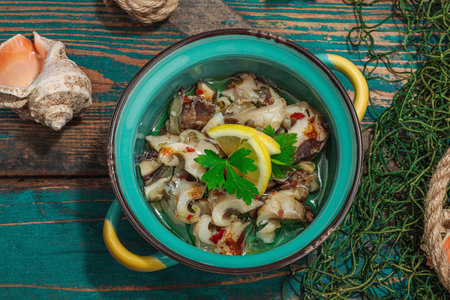 Rapana clam meat with oil, spices and greens. Healthy seafood rich of omega. Marine decor, hard light, dark shadow, old wooden boards, top viewの写真素材