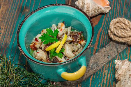 Rapana clam meat with oil, spices and greens. Healthy seafood rich of omega. Marine decor, hard light, dark shadow, old wooden boards, close upの写真素材