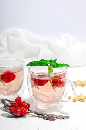 Strawberry tea concept. good morning concept. Teapot, ripe fruits, healthy beverage. Hard light, dark shadow, white background, close upの写真素材