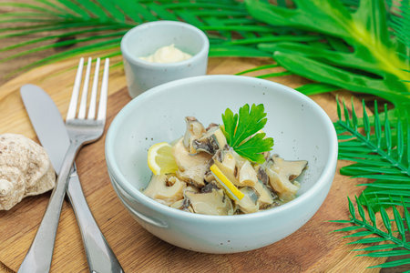Rapana clam meat with oil, spices and greens. Healthy seafood is rich in omega. Marine decor, wooden background, flat lay, close upの写真素材