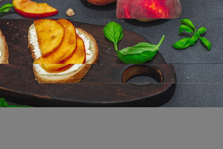 Fresh bread sandwiches with sweet peach slices, cream cheese and basil leaves. Good morning breakfast concept. Hard light, dark shadow, black stone concrete background, copy spaceの写真素材