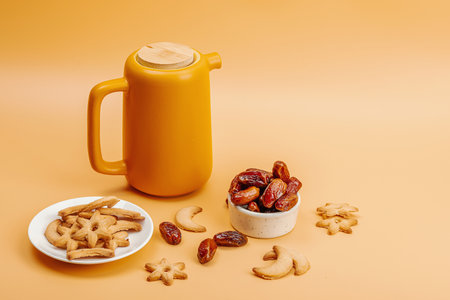 Black hot tea with dates and cookies. Traditional Ramadan Kareem concept snack for Iftar or Suhoor meal on light orange background. An arabian sweet treat, flat lay, copy spaceの写真素材