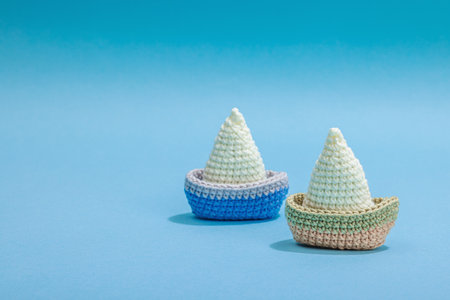 Handmade marine concept. Crocheted boats, nautical style, traditional sea decor. Hard light, dark shadow, trendy blue background, copy spaceの写真素材
