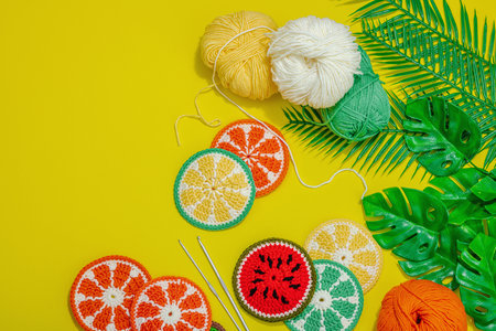 Handmade summer background. Slices of crochet fruits, traditional accessories, bright yellow color. Balls of threads, hard light, dark shadow, flat lay, top viewの写真素材