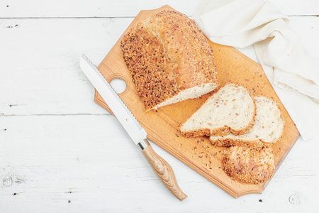 Fresh bread with various seeds. Home baking gluten free concept, hobby. Wooden cutting board, white...