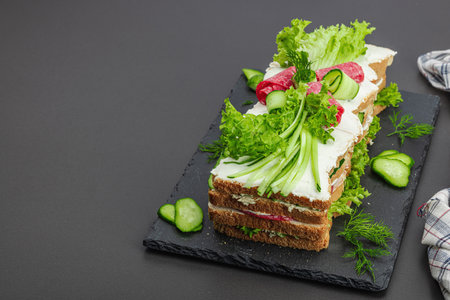 Swedish sandwich cake Smorgastarta. Traditional served cold snack, ready to eat. Modern stand, festive food, black stone concrete background, copy spaceの写真素材