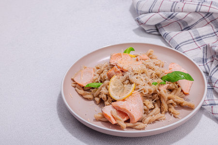 Plant based pasta with salmon, pesto and parmesan cheese. Ready to eat healthy food, served portion on stone table. Hard light, dark shadow, flat lay, copy spaceの写真素材