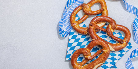 Traditional Oktober fest Pretzels. German festival food concept. Trendy hard light, dark shadow, light stone concrete background, banner formatの写真素材