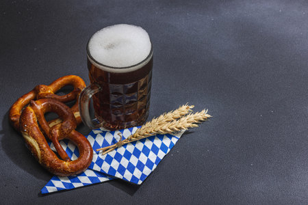 Traditional Oktober fest set. Pretzels and beer, German festival food concept. Trendy hard light, dark shadow, dark stone concrete background, copy spaceの写真素材