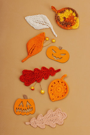 Handmade autumn background. Set of different fall knitted and crocheted fall leaves and wooden pumpkins. Craft, hobby concept, traditional decor on light beige background, top viewの写真素材