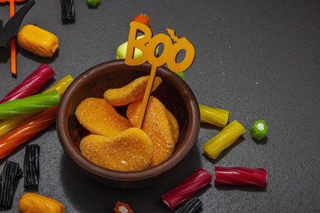 Traditional festive composition for Halloween party. Sweet seasonal food, homemade autumn decor. Hard light, dark shadow, black stone concrete background, flat lay, close upの写真素材