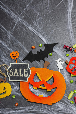 Sale concept, traditional festive composition for Halloween party. Funny seasonal props, homemade autumn decor. Hard light, dark shadow, black stone concrete background, flat lay, top viewの写真素材