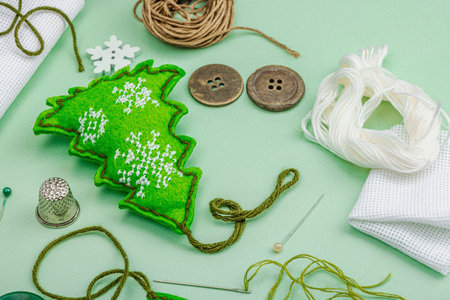 Traditional New Year composition.Festive handmade decor, felt Christmas trees embroidered with a cross. Holiday time concept, light green background, close upの写真素材