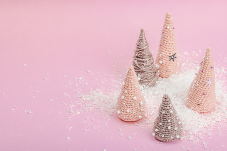 Handmade winter composition. Set of crocheted Christmas trees, artificial snow on pink background. Creative hobby concept, top viewの写真素材