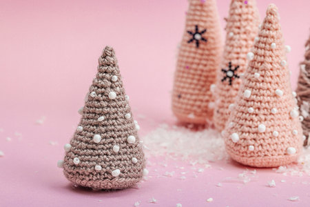 Handmade winter composition. Set of crocheted Christmas trees, artificial snow on pink background. Creative hobby concept, close upの写真素材