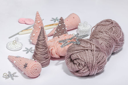 Set of clew of thread for knitting. Crocheted Christmas trees, beads, handmade, winter hobby concept. Props and special craft tools on light gray background, close upの写真素材
