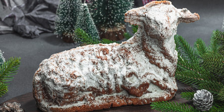 Christmas lamb cake with traditional New Year decor. Baked sweet dessert with sugar icing. Festive background, winter holiday symbol. Dark stone concrete background, banner formatの写真素材