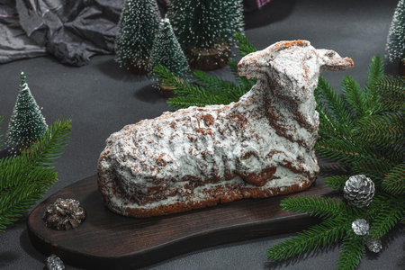 Christmas lamb cake with traditional New Year decor. Baked sweet dessert with sugar icing. Festive background, winter holiday symbol. Dark stone concrete backgroundの写真素材