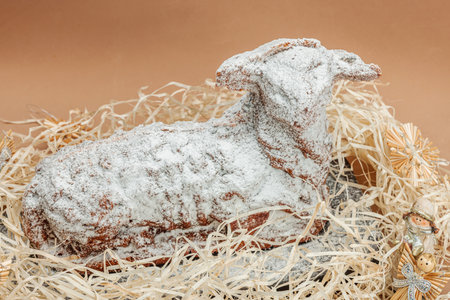 Christmas lamb cake with traditional New Year decor in hay. Baked sweet dessert with sugar icing. Festive background, winter holiday symbol. Dark stone concrete backgroundの写真素材