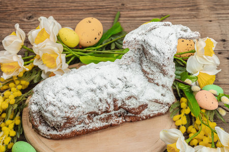 Easter lamb cake with traditional spring decor. Baked sweet dessert with sugar icing. Festive background, classic holiday symbols. Wooden background, close upの写真素材