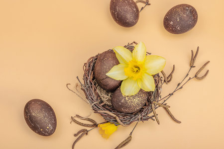 Easter eggs, wooden bunnies and bird's nest with chicken and narcissus flower. Festive concept,...