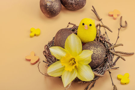 Easter eggs, wooden bunnies and bird's nest with chicken and narcissus flower. Festive concept,...