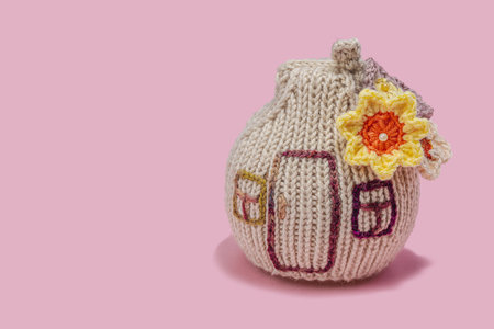 Handmade home spring decor concept. Creative crochet, house figurine, traditional flowers. Festive greeting card, gentle pastel pink background, copy spaceの写真素材