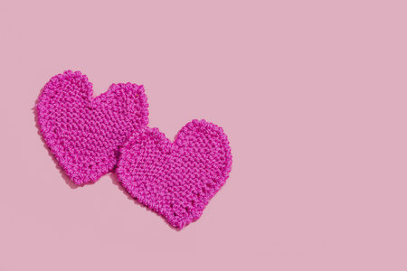 Handmade Valentines Day concept. Creative knitted hearts, spring crafting. Festive greeting card, pink background, hard light, dark shadow, flat lay, top viewの写真素材