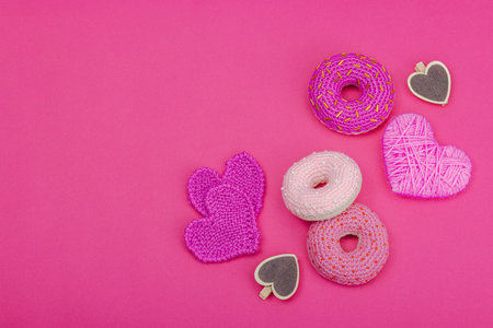 Handmade crocheted donuts with hearts. Festive Valentines or Mothers Day, greeting card, creative craft concept. Magenta background, flat lay, top viewの写真素材