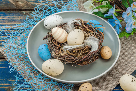 Easter table setting with eggs, bird's nest and blooming branch. Traditional festive symbols,...