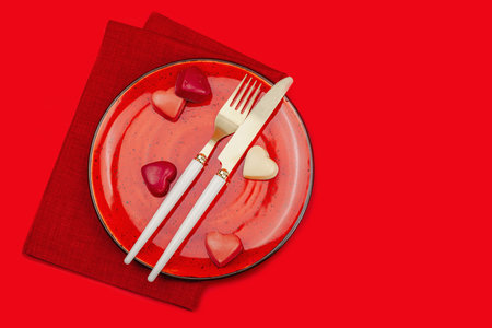 Minimalist spring table setting with sweet chocolate candies. Traditional festive symbol, greeting card, flat lay. Passion red background, top viewの写真素材