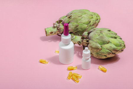 Dietary supplements Artichoke leaf extract capsules. Alternative medicine, beauty herbal lifestyle, healthy self care. Hard light, dark shadow, pink background, flat lay, copy spaceの写真素材