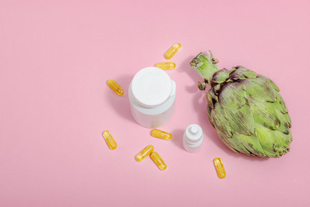 Dietary supplements Artichoke leaf extract capsules. Alternative medicine, beauty herbal lifestyle, healthy self care. Hard light, dark shadow, pink background, flat lay, top viewの写真素材