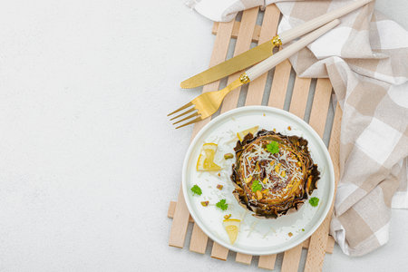 Delicious baked artichoke with parmesan cheese and pistachio. Olive oil, garlic, parsley and lemon. White wooden background, ready to eat vegan food, top viewの写真素材