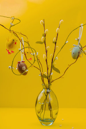 Traditional Easter tree composition with willow branches, handmade eggs and birds. Bright yellow background, place for textの写真素材