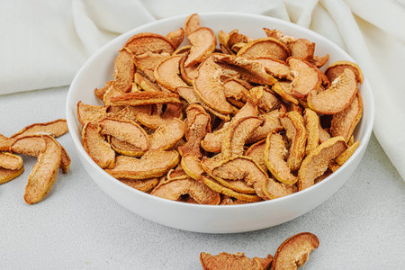 Dry pieces of apple in a bowl. Healthy food diet, vegan lifestyle, lose weight concept. White stone...