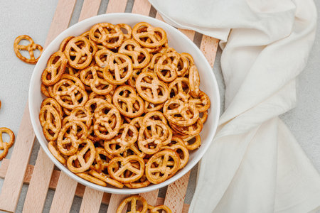 Tasty mini pretzel in a bowl. Traditional food, vegan lifestyle, Oktoberfest symbol concept. White stone concrete background, top viewの写真素材