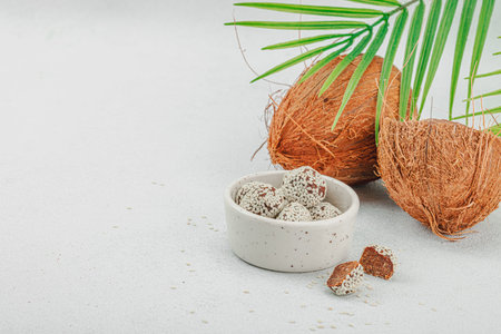 Vegan coconut candies in sesame seeds. Ready to eat food, healthy lifestyle concept. White stone concrete background, copy spaceの写真素材