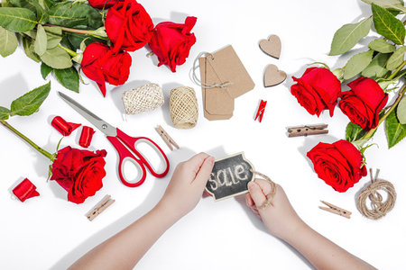 Gift design concept. The child is holding a sign with the inscription Sale in her hands. Handmade, creative space, flat lay, white background, top viewの写真素材