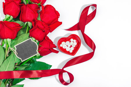 The concept of a romantic date. Bouquet of red roses, small blackboard. Trendy hard light, dark shadow, white background, flat lay, top viewの写真素材