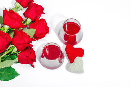 The concept of a romantic date. Two glasses of wine, handmade hearts, a bouquet of red roses. Trendy hard light, dark shadow, white background, flat lay, top viewの写真素材