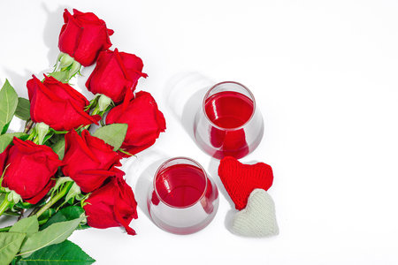 The concept of a romantic date. Two glasses of wine, handmade hearts, a bouquet of red roses. Trendy hard light, dark shadow, white background, flat lay, top viewの写真素材