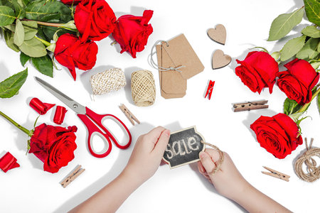 Gift design concept. The child is holding a sign with the inscription Sale in her hands. Handmade, creative space, flat lay, white background, top viewの写真素材
